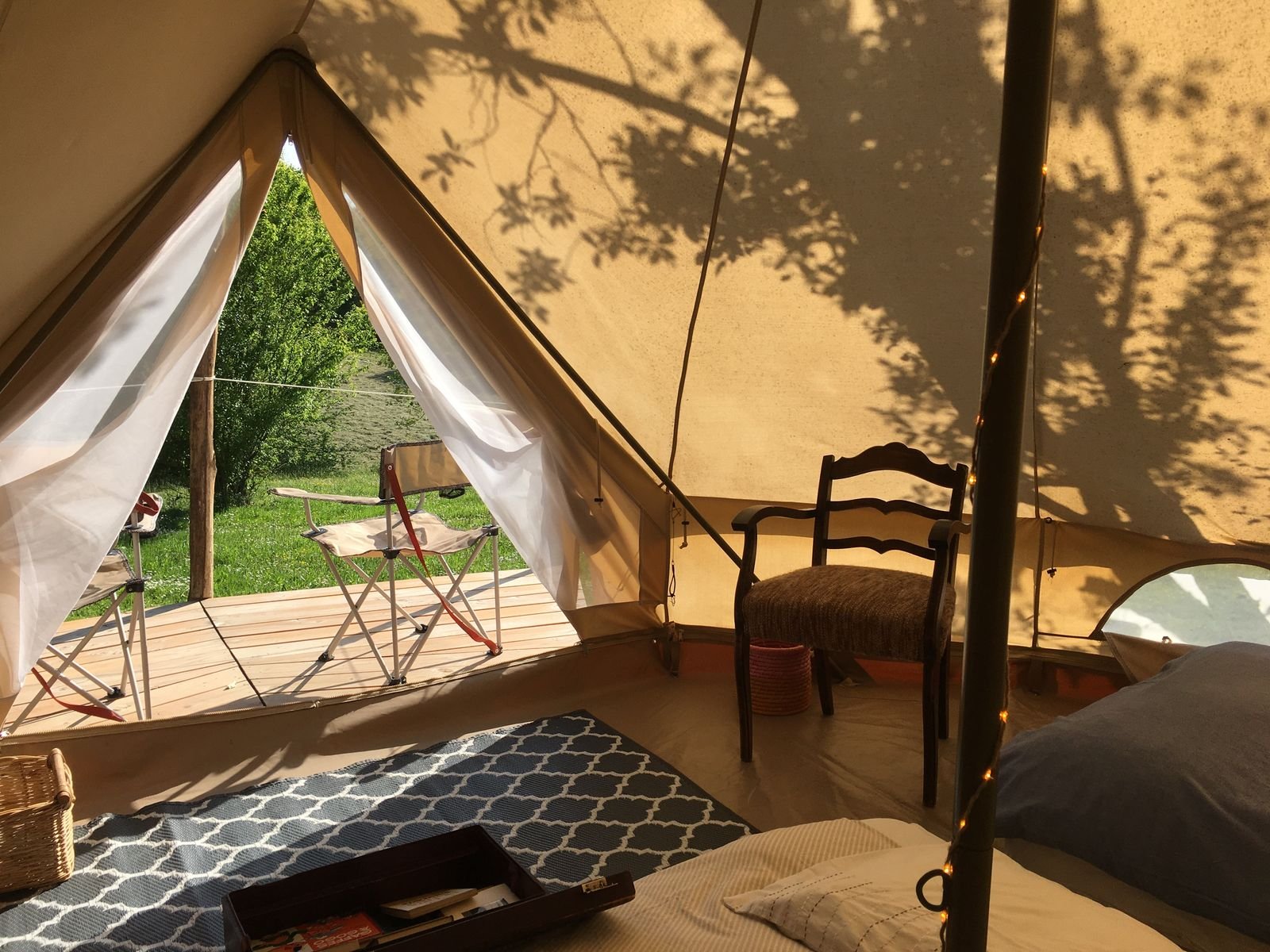 Intérieur de la tente tipi baigné de soleil, ouverte sur le jardin