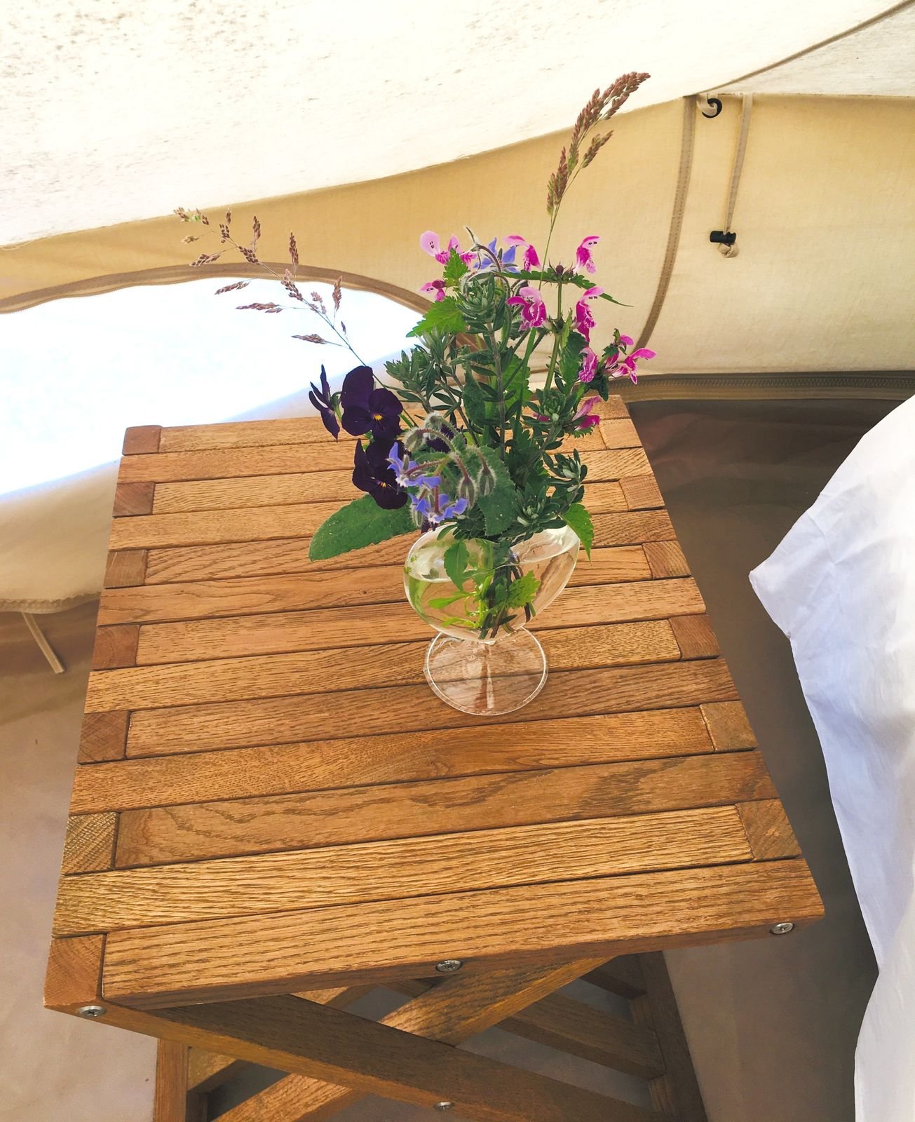 Table en bois et bouquet de fleurs des champs dans la tente tipi