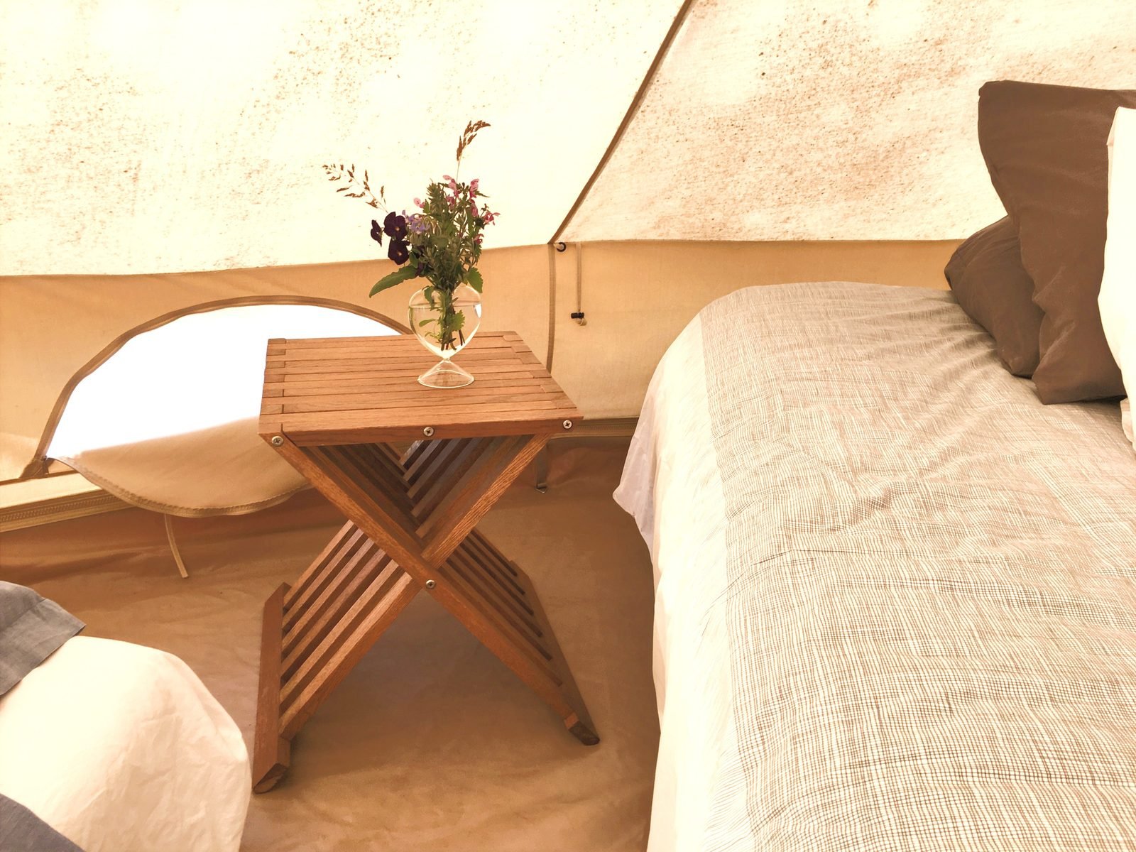 Table en bois et lit préparé à l'intérieur de la tente tipi