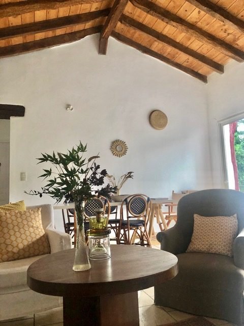 Salon de la maison basque Iturria avec table, fauteuils et bouquet de fleurs